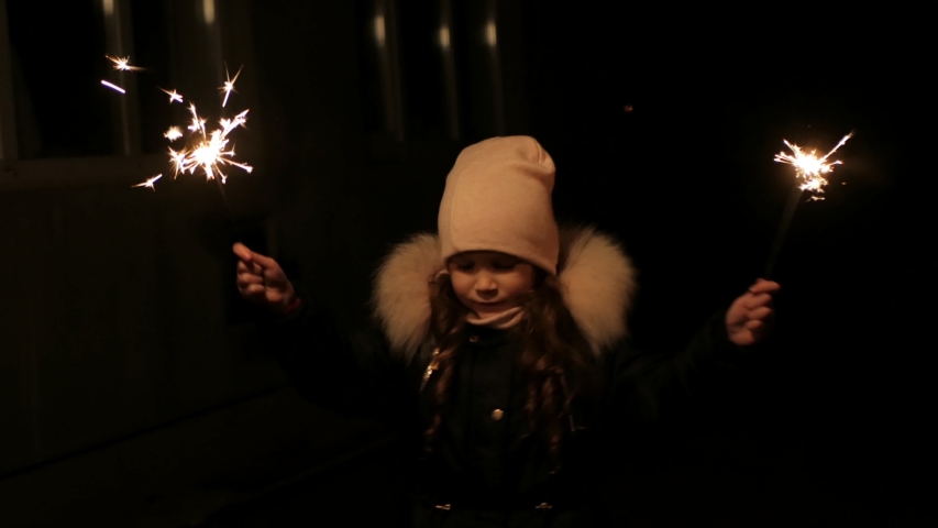Girl with burning sparklers on the street on Christmas night