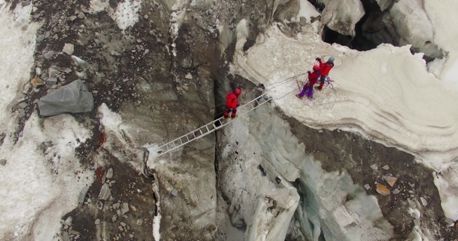 Himalayan mountaineers at Himalayas, upper Himalayan Range, Uttarakhand crossing ice mountains peaks (ice Craft) through ladder support. Experienced mountaineers.Professional mountaineers at Himalaya  | Shutterstock HD Video #1044315493