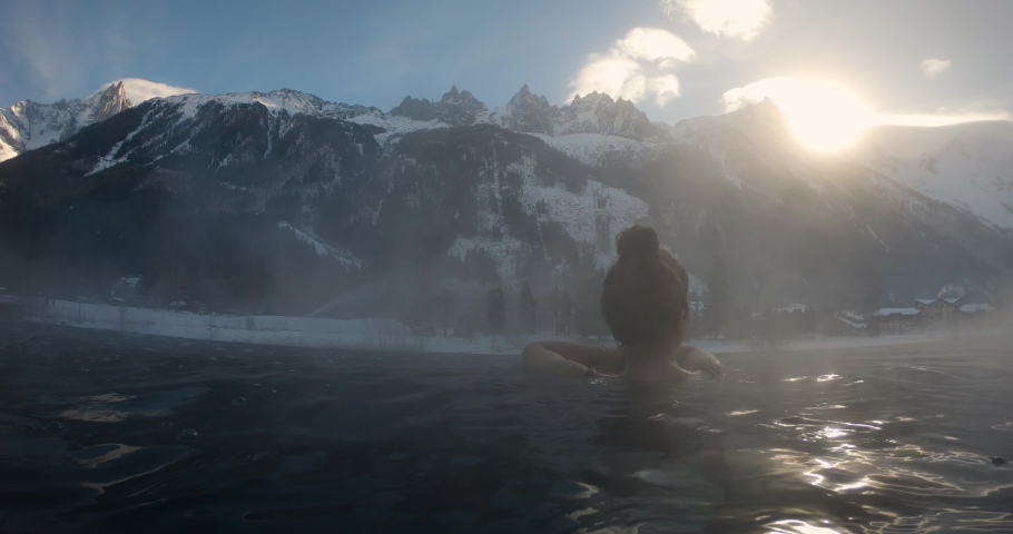 An young female is enjoying and having relax in a hot bath tube in a luxury wellness center during vacation in the mountains. Concept of holidays and wellbeing.