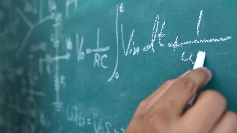 The engineer is calculating the result of the equation to design the electronic circuit, Men writing and sophisticated mathematical formula on chalkboard.