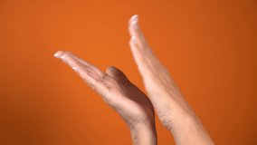Closeup view of white adult woman clapping hands isolated at bright orange background. Real time 4k video footage.