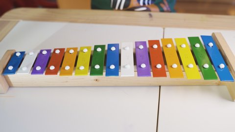 Child playing with a colorful xylophone and learning music. Child development, learning to play a musical instrument