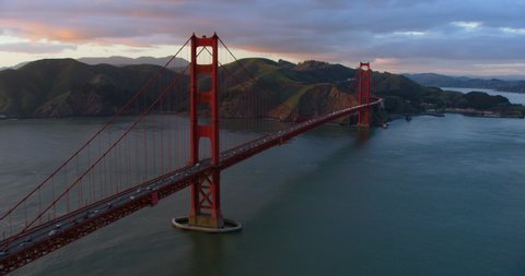 Aerial view of the magnificent Golden Gate Bridge with a cargo ship passing under it. This bridge connects the San Francisco peninsula to Marin County. US route 101 and SR 1 full of cars. Shot on 8K.