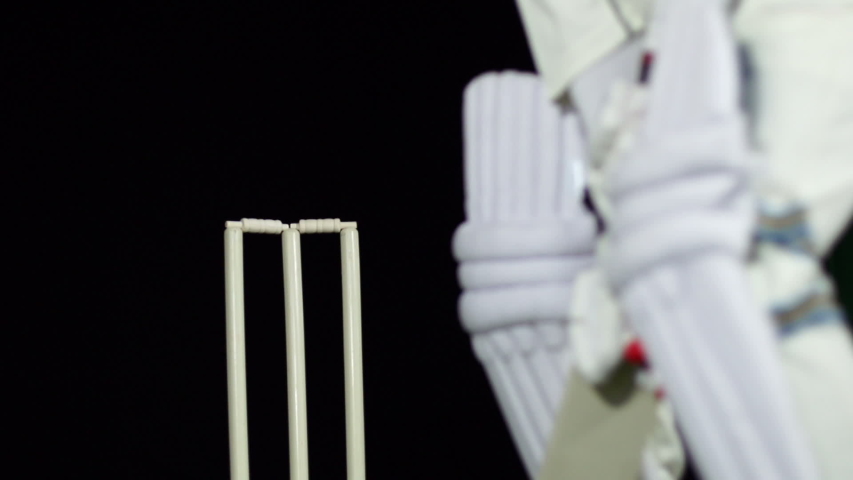 Cricket Batsman bowled out - Wicket. The ball hits the stumps. Black background. Dressed in white. Close up Royalty-Free Stock Footage #1044349798
