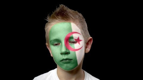  Sad fan of the football team of Algeria. A child with a face painted in national colors. A frustrated fan in despair from losing his favorite team. Crisis, despair, hopelessness.
