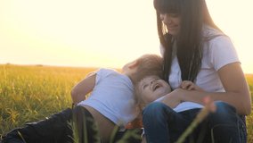 happy family mom and children laughing outdoors in the park slow motion video. mom tickles daughter and son lying on the grass funny funny video smiles laugh. little boy and girl with mom laugh