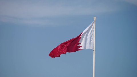Elegant Qatar flag flying in the sky on a bright sunny day in slow motion