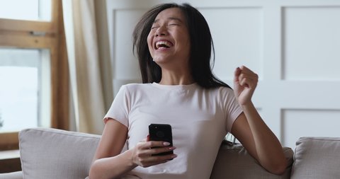 Excited young asian lady user winner hold smartphone feel amazed with good surprise social media news mobile online bid app win looking at cellphone laughing celebrating success victory concept