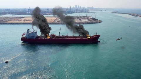 Aerial Footage over Oil Tanker Ship Burning Under attack Close to Harbor
Aerial view with visual effect elements simulates realistic vision of Oil Tanker on fire with smoke  and Helicopter Close to Ha