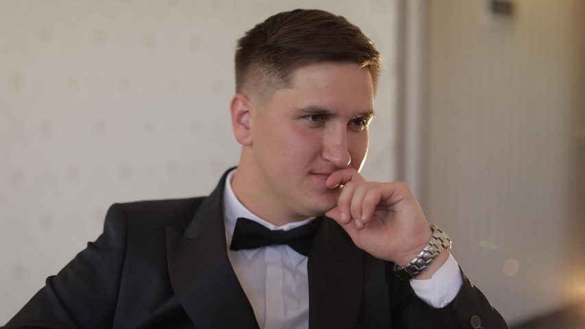 Handsome groom looking at camera. White shirt with black bow tie. Wedding morning. Businessman. Slow motion