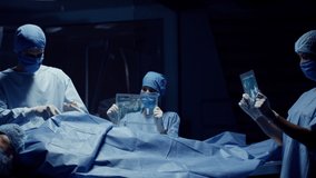 Team of Medical Surgeons use Futuristic Holographic Touchscreen Tablets to Examine Patient during Medical Procedure. Transparent Screens showing ECG and Medical Data Activity. Shot on RED Epic W. - Powered by Shutterstock - Get 15% off with code: PIKWIZARD15