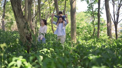 happy asian family with one child walking relaxing and enjoying nature in woods