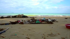 Trash on the beach. Static video in 4k of trash on the sand beach with the waves moving in the background