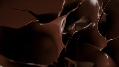 Super Slow Motion Shot of Raw Chocolate Chunks Falling into Melted Chocolate 