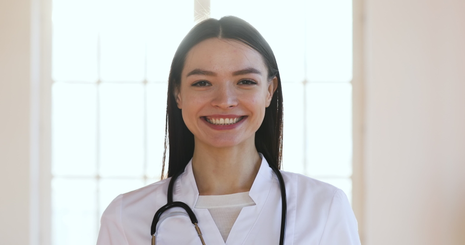 Serious confident smiling young woman wear white medical coat with stethoscope looking at camera, happy adult lady professional medic clinic staff female nurse or doctor posing for close up portrait Royalty-Free Stock Footage #1044437077