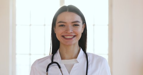 Serious confident smiling young woman wear white medical coat with stethoscope looking at camera, happy adult lady professional medic clinic staff female nurse or doctor posing for close up portrait