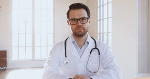 Confident professional medic male doctor wear white uniform consulting patient online doing video conference distance chat talking look at camera, electronic medical appointment concept, webcam view