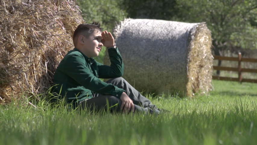 A young boy looks at the rays of the sun sitting on the grass.