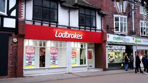 Chester / United Kingdom - December 27 2019: Ladbrokes gambling company shop front in Chester and people walking by.