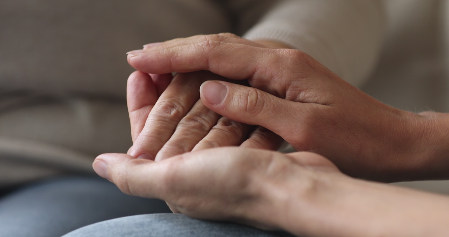 Two women generation young adult woman daughter or carer holding stroking senior grandparent female hand helping in disease, sharing problem grief, giving support and comfort concept, close up view | Shutterstock HD Video #1044454939