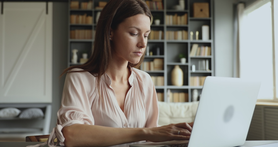 Young adult business woman typing on laptop computer working in internet, beautiful female professional user lady using pc technology doing online job in office or browsing web sit at home table | Shutterstock HD Video #1044454966
