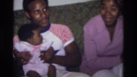 ATLANTA GEORGIA USA-1975: African American Couple Sitting On The Couch While Carrying Their Baby