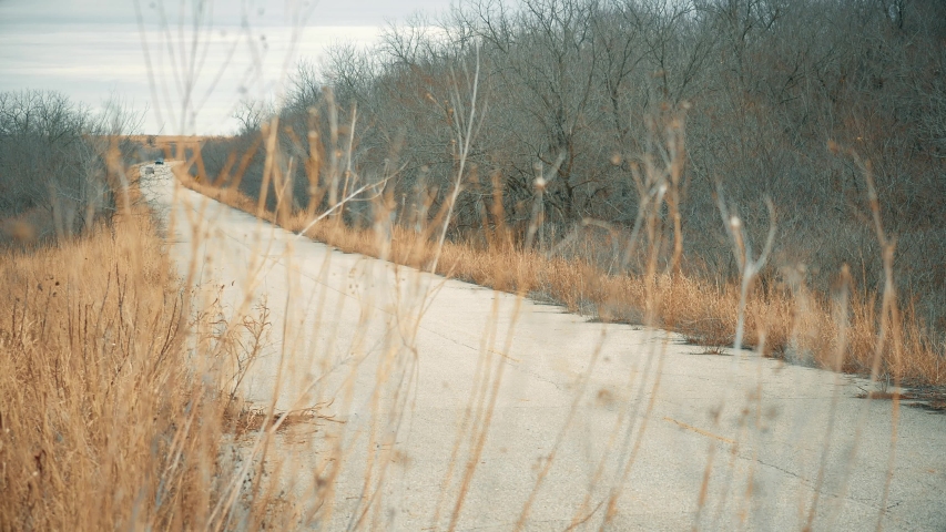 Police car chasing muscle car at high speed down rural highway.