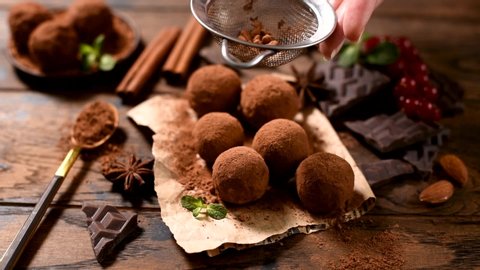Sieving cocoa powder on chocolate truffles. Homemade dark chocolate truffles, chocolate candy balls. Vegan and vegetarian chocolate