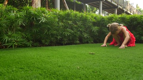 Girl child tumbles sometime on green grass. Child make somersault