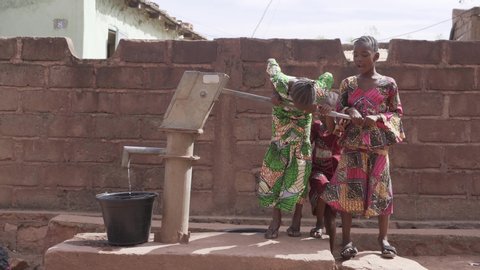 Three Little African Girls Troubeling Pumping Up Water At The Village Well