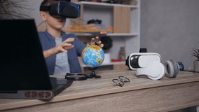Close up of good-looking smart 12-aged boy in blue shirt which sitting at his workplace get acquainted with the structure of earth using little globe and virtual 3d glasses - Powered by Shutterstock - Get 15% off with code: PIKWIZARD15