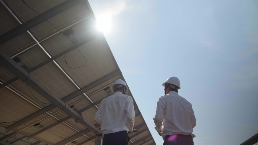 Technician and investor walking in Solar cell Farm through field of solar panels checking the panels at solar energy installation.Solar cells will be an important renewable energy of the future. Royalty-Free Stock Footage #1044485071