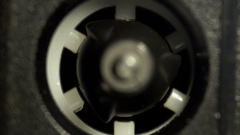 Macro shot of a vintage audio cassette reel rotating in the tape recorder. Concept of playing music, recording a conversation, listening sounds. 4K resolution video.