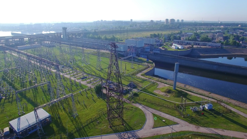 An aerial circular orbit view, high voltage electric power tower with infographic power flows, hydroelectric power station and electric substation with tall pylons and hog voltage distribution cables. | Shutterstock HD Video #1044489391