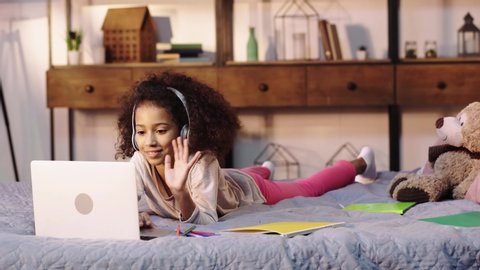 african american child having video call on laptop in bed