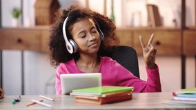 happy african american child listening music and showing peace sign