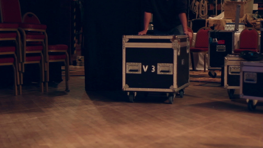 Roadie / Stage Crew pushing a Flightcase on a stage - The Stage Hand is helping at a gig / concert.