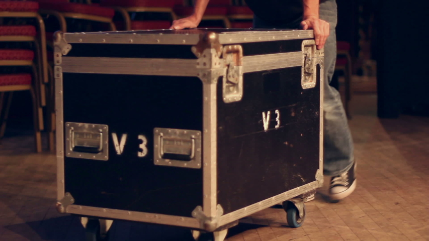Roadie / Stage Crew pushing a Flightcase on a stage - The Stage Hand is helping at a gig / concert.