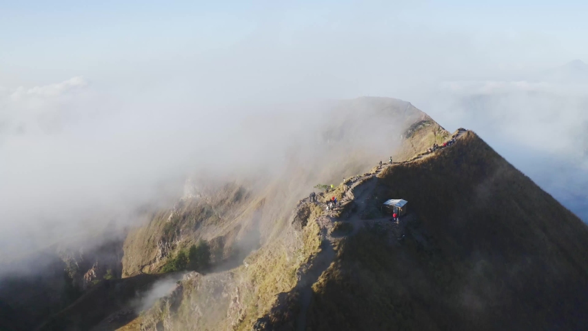 Morning Batur volcano mountain in clouds with hikers tourist aerial view