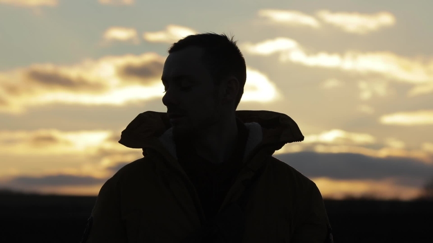 Silhouette of man wearing headphones listening to music at sunset