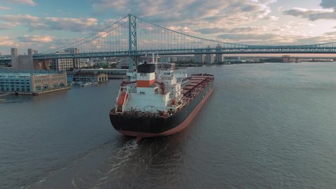 Aerial: Container Ship on the Delaware River crossing the Ben Franklin Bridge. Philadelphia, Pennsylvania, USA