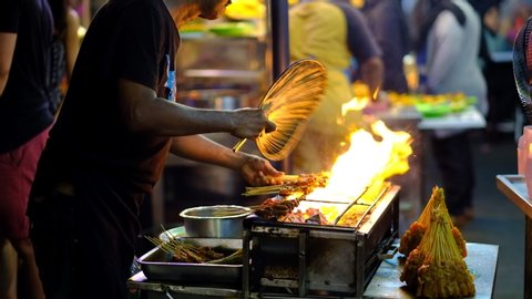 Penang, Malaysia :12 /01 /2020 : 4K Footage of a hawker fanning the skewed stick marinated meat or called Satay at Gurney Drive Hawker Market, Penang, Malaysia. 