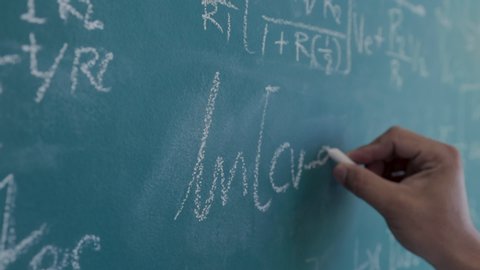 The engineer is calculating the result of the equation to design the electronic circuit, Men writing and sophisticated mathematical formula on chalkboard.