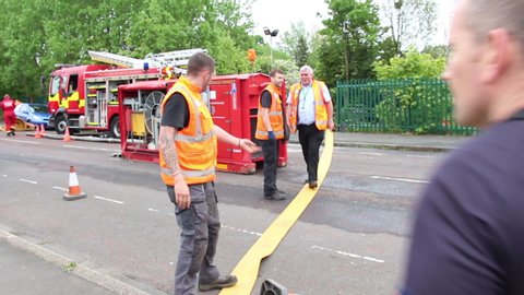 Newcastle Upon Tyne , Tyne and Wear, UK - May 17th 2017 
Tyne and Wear Fire Service struggle with the huge heavy hose. They are attending a flooded metro railway line in Newcastle. 