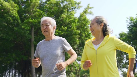 happy senior asian couple exercising running outdoors
