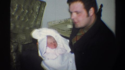 GAINSVILLE FLORIDA USA-1974: Man Sideburns Talking To Newborn Baby Bundled In White Blanket