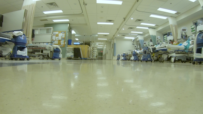 Low angle view as a doctor and nurse transfer a patient on a gurney through the hospital. Royalty-Free Stock Footage #1044556135