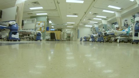 Low angle view as a doctor and nurse transfer a patient on a gurney through the hospital.