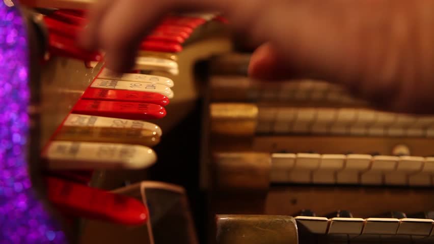 An organist works the organ stops of a pipe organ.