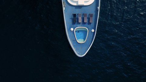 Straight down birds eye view from drone on luxurious expensive yacht cruising in ocean. Beautiful woman in bikini, lays on deck, relax and sun tan. Life of rich and famous
